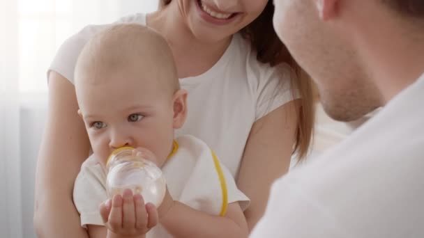 Adorable bébé bébé buvant de l'eau de bouteille et riant avec ses parents — Video