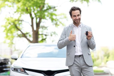 Araba kiralama servisi. Otomobil satıcısı anahtarlarını sahibine veriyor. Galeride müşterinin anahtarı ellerindedir.