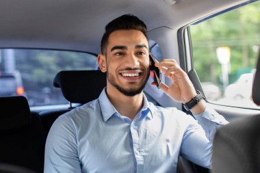 Neşeli bir ortadoğu yöneticisi iş ortağıyla telefonda konuşuyor.