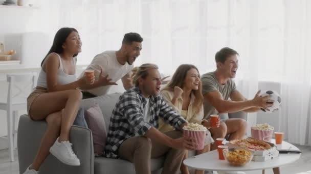 Emocjonalna grupa wielokulturowych przyjaciół oglądających mecz piłki nożnej razem w domu — Wideo stockowe