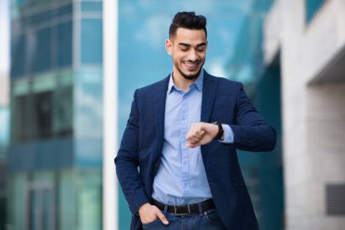 Neşeli Orta Doğulu CEO zamanı kontrol ediyor, iş görüşmesi yapıyor.