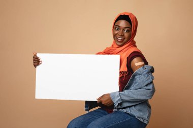 Güzel siyah Müslüman kadın aşılandı, elinde boş bir levha vardı.