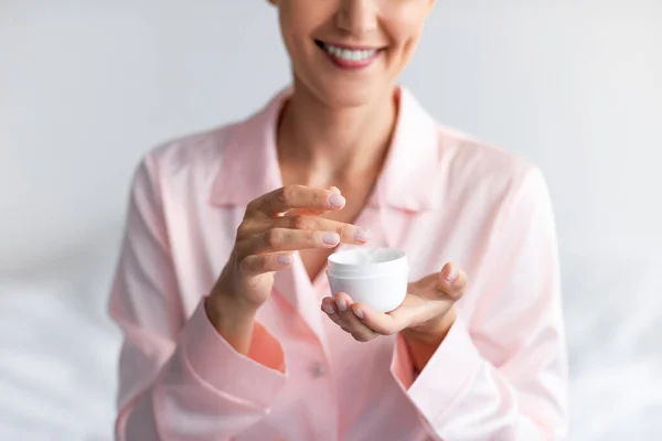 Sluiten van glimlachende vrouw met crème pot — Stockfoto