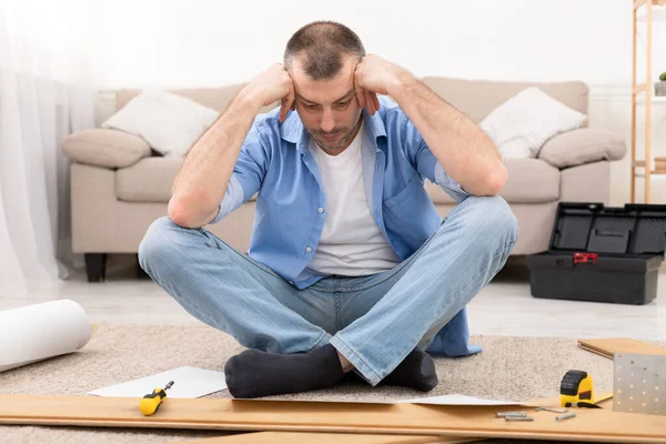 Confused Man Having Hard Time Assembling Furniture Reading Manual Indoor