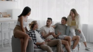 Bir grup mutlu çok kültürlü arkadaş evde sohbet ediyorlar.