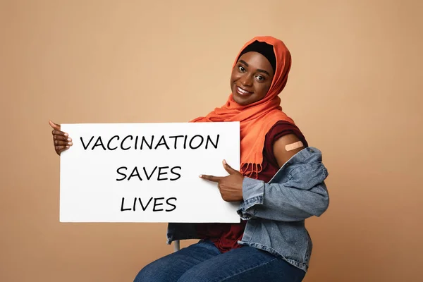 Happy muslim woman with plaster on shoulder holding placard — Stock Photo, Image