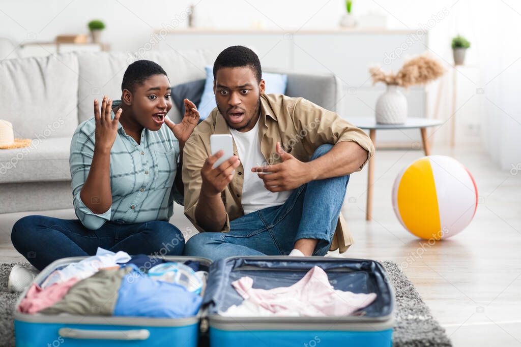 Black Couple Using Phone Reading Message About Flight Cancellation Indoor