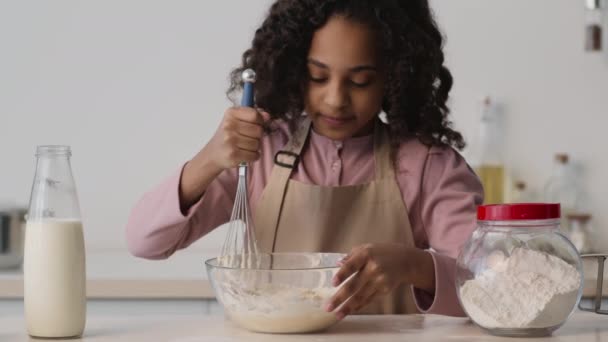 Micuță fată africană americană pregătind coacerea la bucătărie, încercând gustul de patiserie crudă și zâmbind, bucurându-se de ea, mișcare lentă — Videoclip de stoc