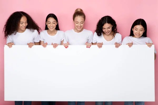 Fem kvinnor som visar vit tavla för text på rosa bakgrund — Stockfoto