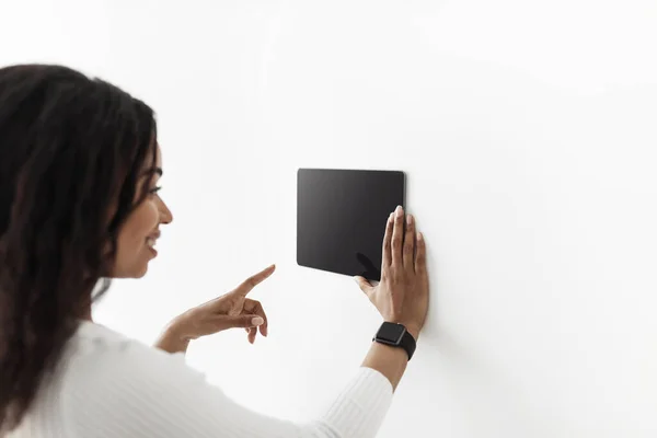 Mujer afroamericana usando tableta digital con pantalla negra en blanco con aplicación de sistema de control del hogar inteligente, maqueta —  Fotos de Stock
