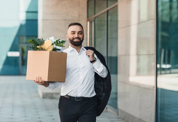 Feliz hombre de negocios de mediana edad caminando al aire libre con caja de cosas como salir del centro de negocios, dejar el trabajo y celebrar — Foto de Stock