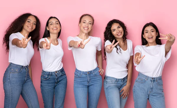 Mulheres Multirraciais bem sucedidas Gesturing Victory Sign Over Pink Studio Background — Fotografia de Stock