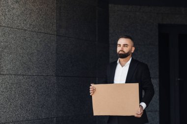 İşadamı boş karton tabela gösteriyor. Sokakların kilitlenmesini protesto ediyor.