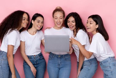 Pembe Arkaplanda Birlikte Duran Dizüstü bilgisayar kullanan Çok Irklı Kadınlar