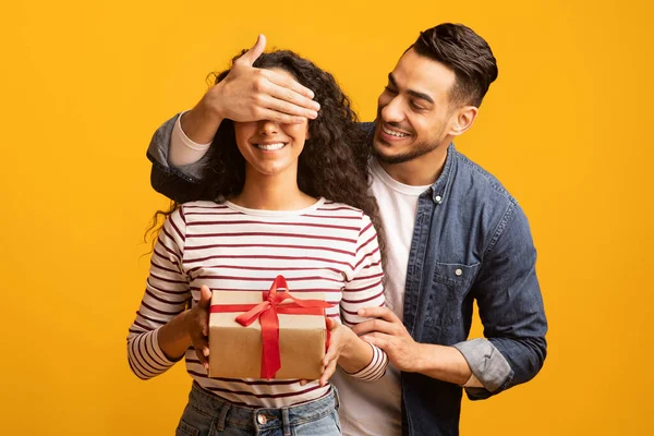 Överraskningsgåva. Romantisk arabisk man täcker sina flickvänner ögon och ger present — Stockfoto