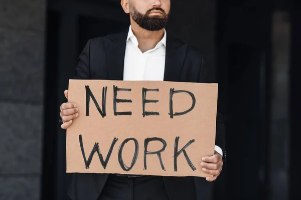 Necesito trabajo. Trabajador de oficina irreconocible sosteniendo cartel de cartón, parado al aire libre cerca del centro de negocios, cosecha — Foto de Stock