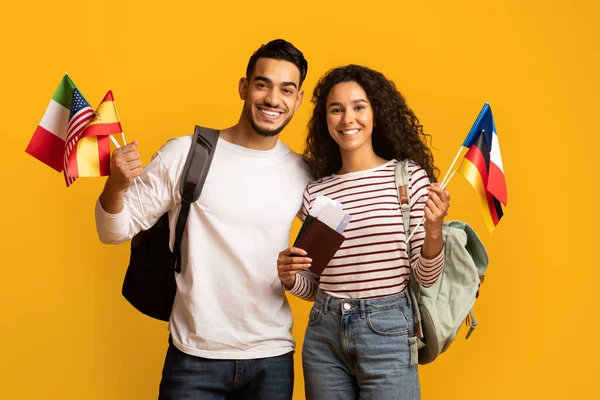 Viajar no estrangeiro. Turistas árabes casal segurando passaportes com bilhetes e bandeiras internacionais — Fotografia de Stock