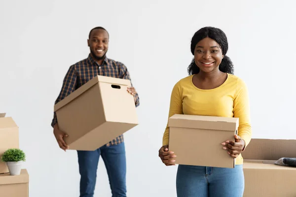 Fröhliche schwarze Ehepartner tragen Kisten mit Habseligkeiten, während sie in eine neue Wohnung ziehen — Stockfoto