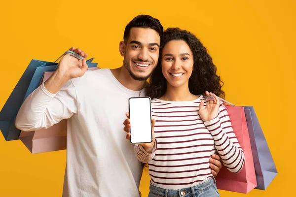 İnternetten alışveriş uygulaması. Neşeli genç Arap çift boş ekranlı akıllı telefon gösteriyor. — Stok fotoğraf