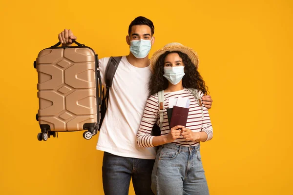 Pareja de turistas árabes felices con máscaras médicas que sostienen maletas y pasaportes —  Fotos de Stock