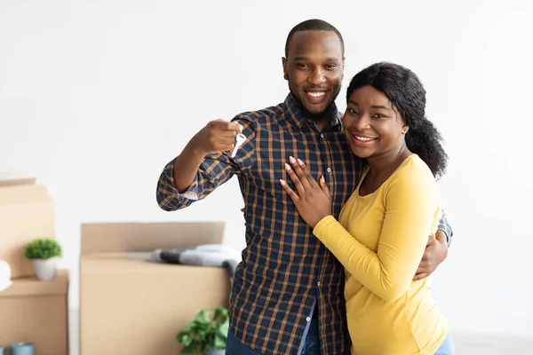 Felizes cônjuges afro-americanos demonstrando chaves de casa na câmera e abraçando — Fotografia de Stock