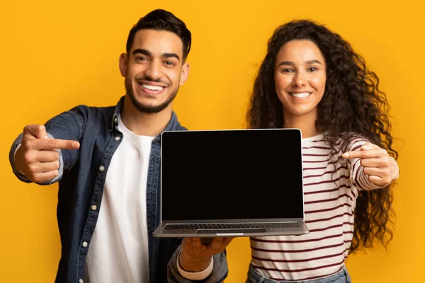 Grande sito web. Sorridente coppia mediorientale che punta al computer portatile con schermo nero — Foto Stock