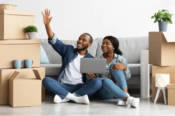 Pareja negra feliz sentada con el ordenador portátil e imaginando diseño en su plano — Foto de Stock