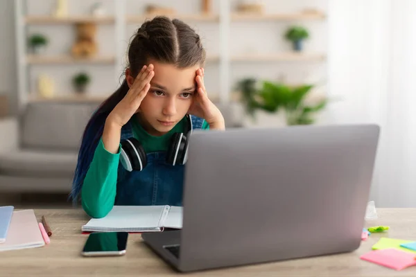 Chica de la escuela cansada haciendo la tarea agarrando su cabeza usando PC — Foto de Stock