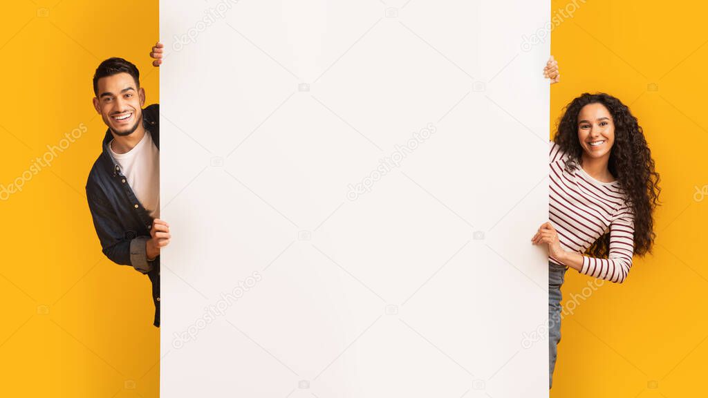 Cheerful Young Arab Couple Standing Near Big White Advertisement Board