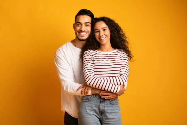 Porträt eines fröhlichen jungen arabischen Paares, das sich umarmt und in die Kamera lächelt — Stockfoto