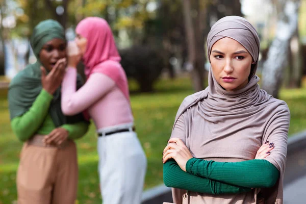 Islamische Damen flüstern hinter dem Rücken ihres unglücklichen Freundes im Freien — Stockfoto