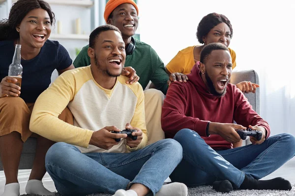 Emotionale afrikanisch-amerikanische Freunde, die zu Hause Videospiele spielen — Stockfoto