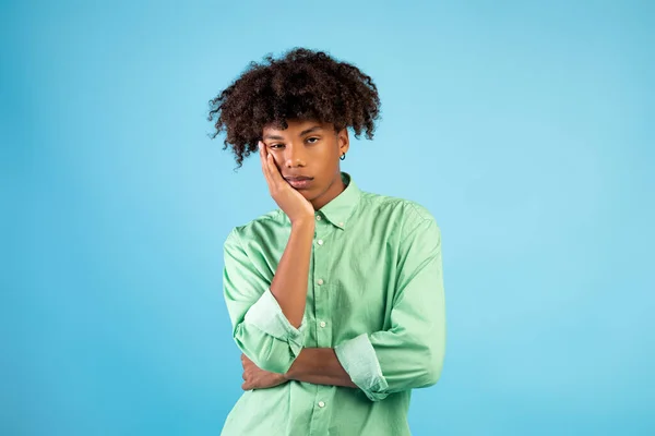 Retrato de preto teen cara sentindo entediado, inclinando-se no seu mão, tendo maçante dia no azul estúdio fundo — Fotografia de Stock