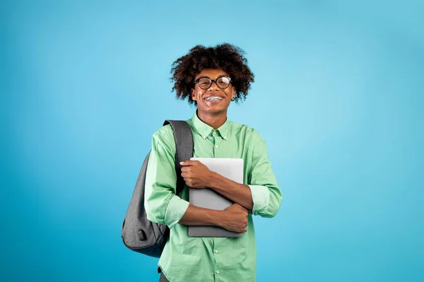 학생들의 생활 방식 개념. 컴퓨터를 들고 파란 배경 위에 서 있는 행복 한 아프리카 계 미국인 남자 — 스톡 사진
