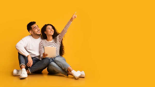 Nice Offer. Excited young arabic couple holding digital tablet and pointing away — Stock Photo, Image
