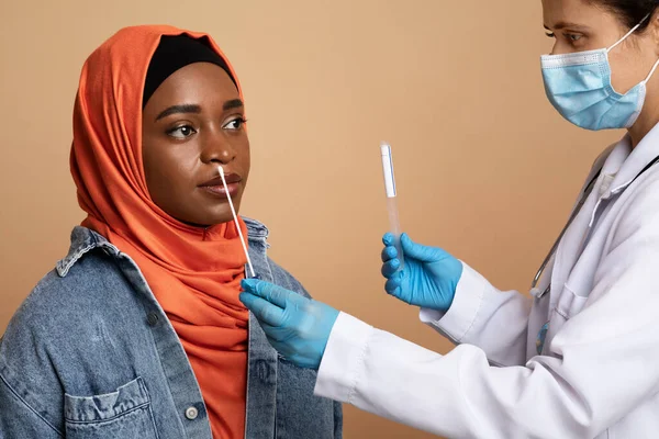 Trabalhador médico que toma cotonete para amostra de coronavírus de mulher muçulmana — Fotografia de Stock