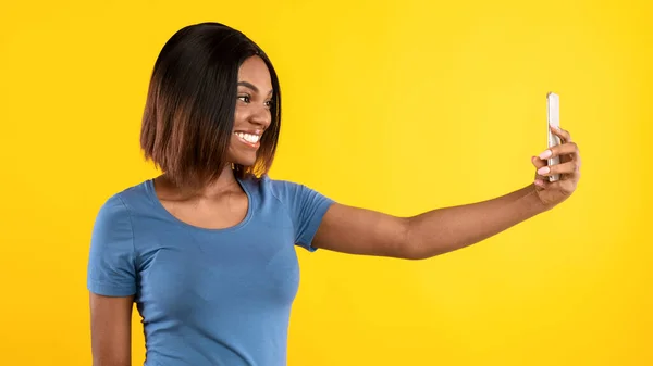 Alegre hembra negra haciendo selfie en Smartphone sobre fondo amarillo — Foto de Stock