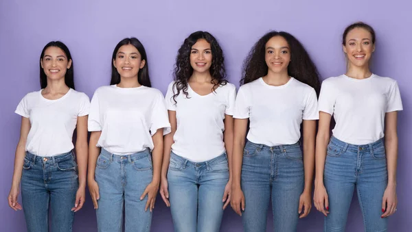 Multicultural señoras jóvenes de pie juntos sobre fondo púrpura — Foto de Stock