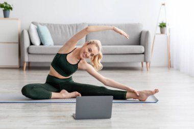 Aktif kadın evdeki oturma odasında esneme egzersizi yapıyor.