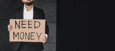 Takım elbiseli tanınmayan bir işadamı elinde tabelayla dışarıda dikilirken paraya ihtiyacı var.