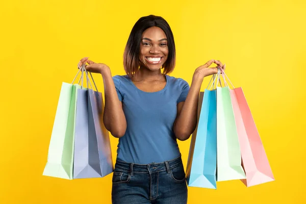 Black Lady rymmer shoppingväskor stående på gul bakgrund — Stockfoto