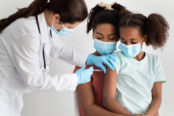 Zwarte familie vaccinatie in de kliniek, het dragen van gezichtsmaskers — Stockfoto