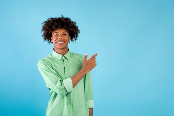 Offre spéciale. Portrait de heureux afro-américain adolescent gars pointant vers l'espace de copie, debout sur fond bleu — Photo