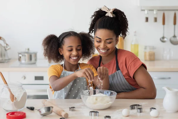 Vidám afro-amerikai anya és lánya sütit sütnek együtt. — Stock Fotó