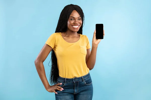 Gelukkig zwart vrouw tonen smartphone leeg scherm op blauwe achtergrond — Stockfoto