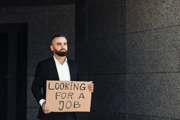 Olycklig förtvivlad affärsman förlorade jobbet innehar söker jobb plakat, står nära businesscenter, fritt utrymme — Stockfoto