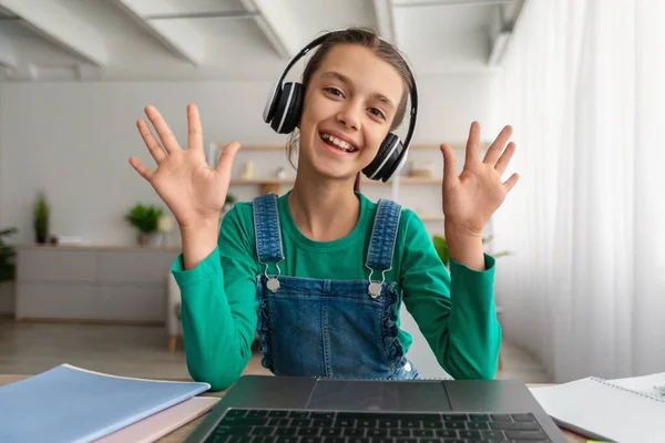 Chica sentada en el escritorio, teniendo videollamada con auriculares —  Fotos de Stock