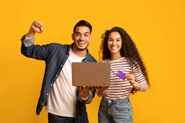 Portret van een vrolijk midden-oosters echtpaar met laptop en creditcard die succes vieren — Stockfoto