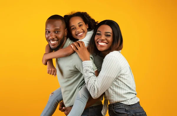Tijd met familie. dolblij Afrikaans amerikaanse familie lachen en poseren voor camera geïsoleerd over gele studio muur — Stockfoto
