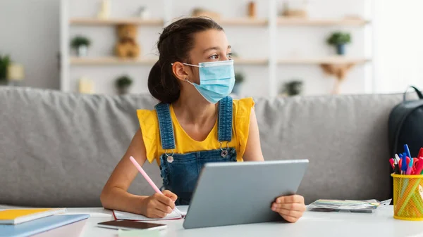 Iskoláslány orvosi maszkban tanul távolról digitális tabletta — Stock Fotó